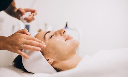 Cosmetologist cleaning face of a woman in a beauty salon